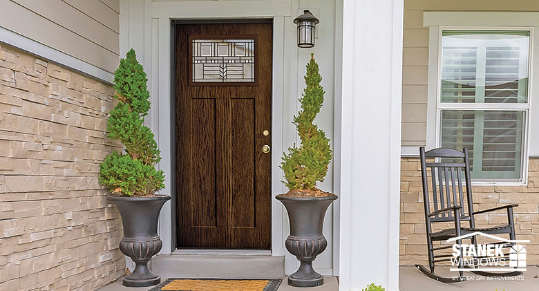 Dark wood front entry door in Shaker style with Art Deco patterned in glass inset.
