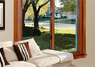 Sliding window from inside a living room with a white couch and brown and white striped pillows.