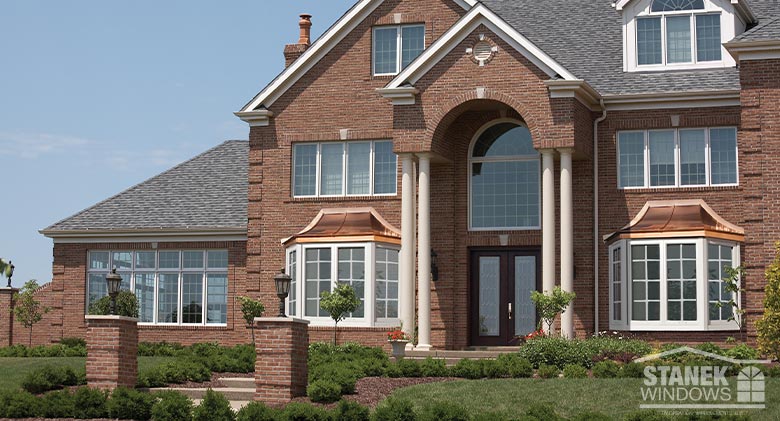 Large brick home with two copper-topped bay windows