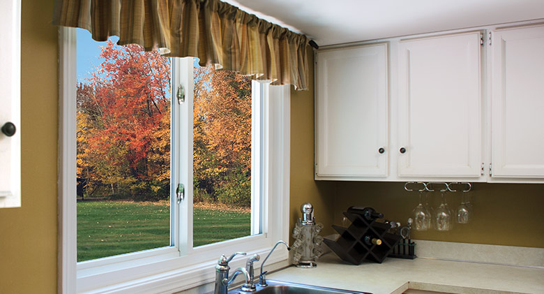 A sliding window over a kitchen sink with a view of autumn leaves.
