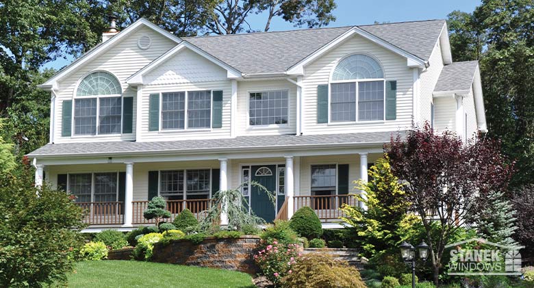 A white colonial home with double-hung and half-circle windows with colonial grids and teal shutters.