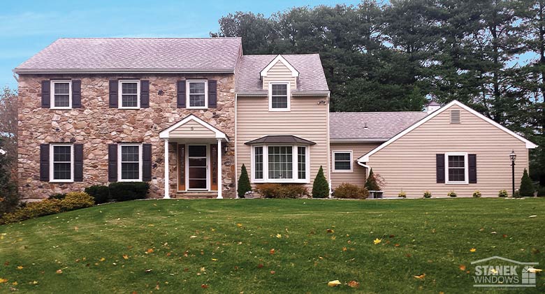 A traditional two-story home with stone and siding, a bay window and double-hung windows.